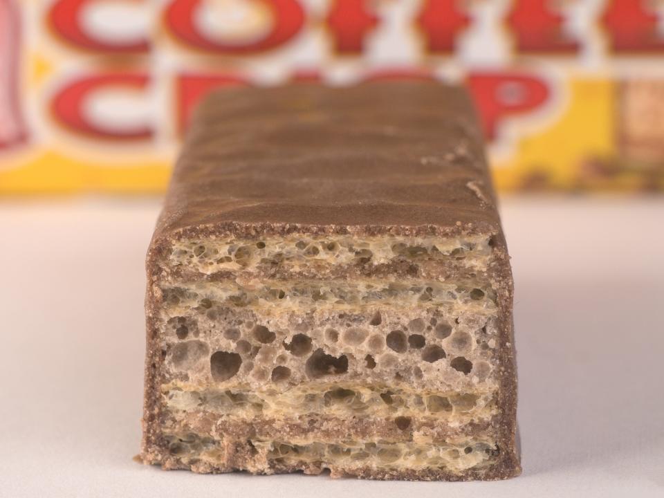 View of a Nestle Coffee Crisp cut in half with yellow packaging in background