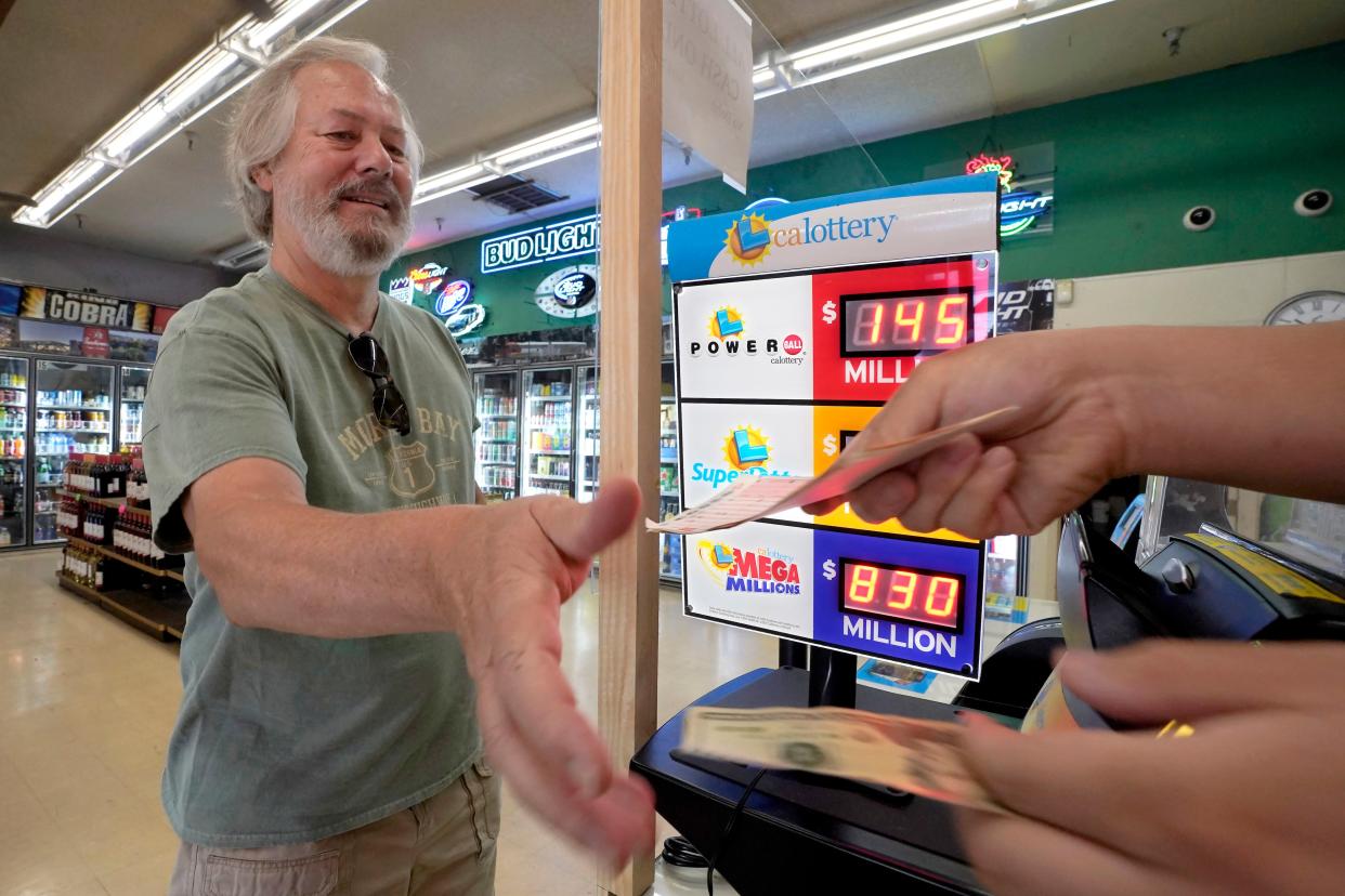 Dave Powell exchanges his cash for Mega Millions lottery tickets at Lichine's Liquors & Deli in Sacramento, Calif., on Tuesday.