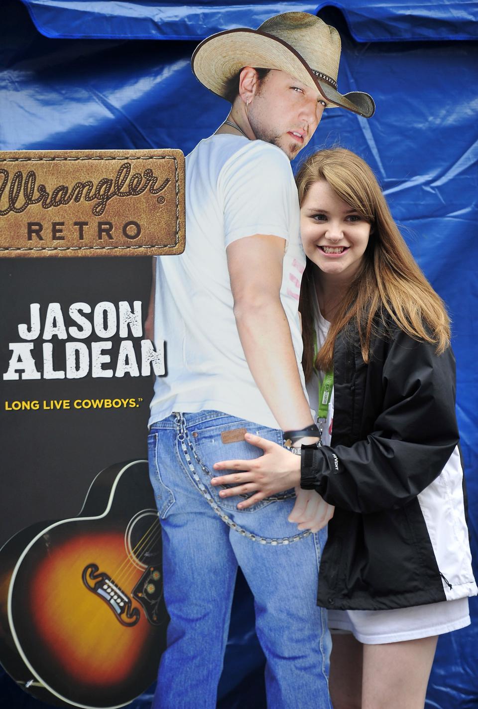 Country music fan Allie Pasley, of Memphis, has her picture taken with a Jason Aldean poster during the CMA Music Festival in Nashville June 5, 2014.