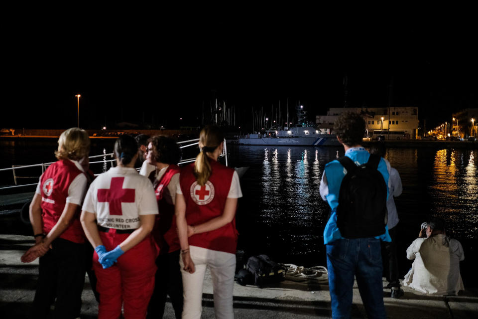 Members of the Red Cross and UNHCR wait outside of a hangar where more than 100 migrants have been temporarily housed as the Greek Coast Guard ship with 79 recovered bodies arrives to a port in Kalamata on June 14.<span class="copyright">Byron Smith—Getty Images</span>