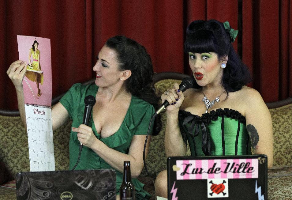 In this March 5, 2012, photo, Nicole Nadreau, left, who goes by the stage name of "Contessa" and Christina Farsciello, who goes by "Judy Pop", look at a pinup calendar during their Internet show in an Ybor City studio in Tampa, Fla. (AP Photo/Chris O'Meara)