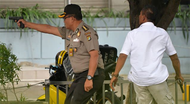 A police officer fires his pistol outside of a cafe in Jakarta. Photo: Getty Images