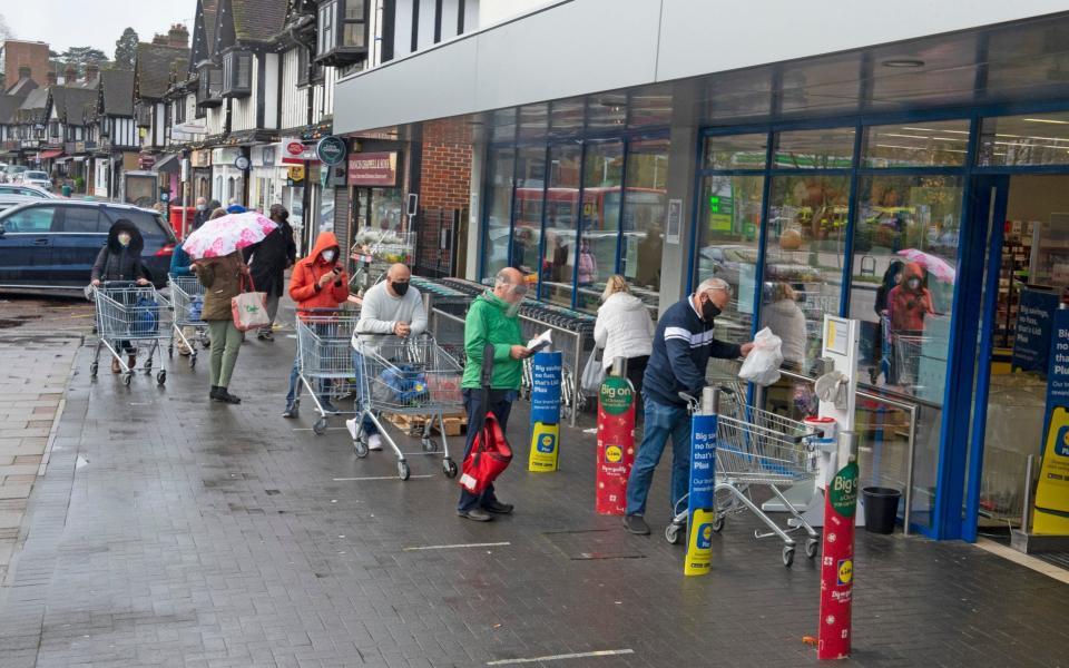 Shoppers queue in the rain outside a LIdl supermarket in Locksbottom, Bromley, London - Grant Falvey/London News Pictures Ltd 