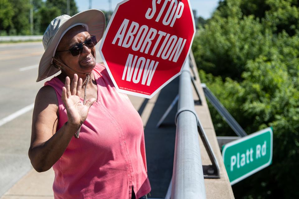 Anti-abortion activist Linda Nealing, of Ypsilanti Township, waves at traffic on Interstate 94 next to a banner that says u0022Abortion takes a human lifeu0022 to celebrates the Supreme Court decision to overturn Roe v. Wade from the Platt Road overpass in Ann Arbor on Friday, June 24, 2022.