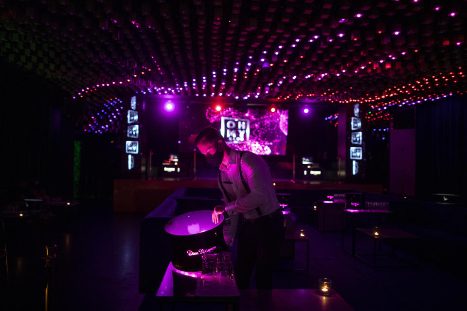 A waiter wearing a face mask to prevent the spread of coronavirus works in a discotheque in Madrid, Spain, early Saturday, July 25, 2020. Nightlife is becoming the new target of Spanish authorities attempting to contain a spike in coronavirus infections since the country ended a lockdown. The Catalonia regional government has shut nightlife venues in Barcelona, and on Friday officials in Madrid said they were considering a similar step. (AP Photo/Manu Fernandez)