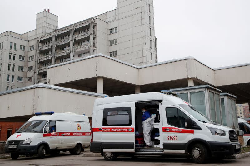 FILE PHOTO: A medical specialist takes her protective gear off in an ambulance parked outside a hospital, amid the outbreak of the coronavirus disease (COVID-19) in Saint Petersburg