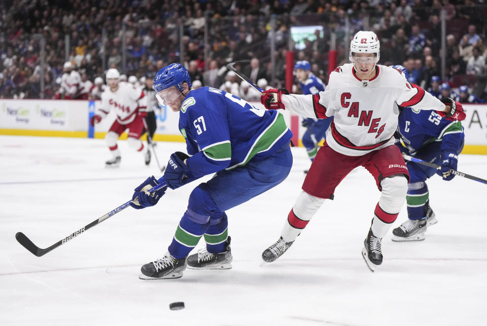 Vancouver Canucks' Tyler Myers, left, and Carolina Hurricanes' Jesperi Kotkaniemi, of Finland, vie for the puck during the third period of an NHL hockey game in Vancouver, British Columbia, Monday, Oct. 24, 2022. (Darryl Dyck/The Canadian Press via AP)