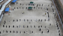 High school students and staff wait in line to receive the coronavirus tests at a makeshift clinic set up on a playground of a school in Sejong, South Korea, Friday, Nov. 27, 2020. South Korea's daily virus tally hovered above 500 for the second straight day, as the country's prime minister urged the public to stay home this weekend to contain a viral resurgence. (Kim Ju-hyung/Yonhap via AP)