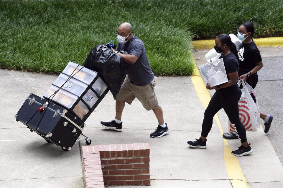 College students with the assistance of family begin moving in for the fall semester at N.C. State University in Raleigh, N.C., Friday, July 31, 2020. The first wave of college students returning to their dorms aren’t finding the typical mobs of students and parents. At N.C. State, the return of students was staggered over 10 days and students were greeted Friday by socially distant volunteers donning masks and face shields. (AP Photo/Gerry Broome)