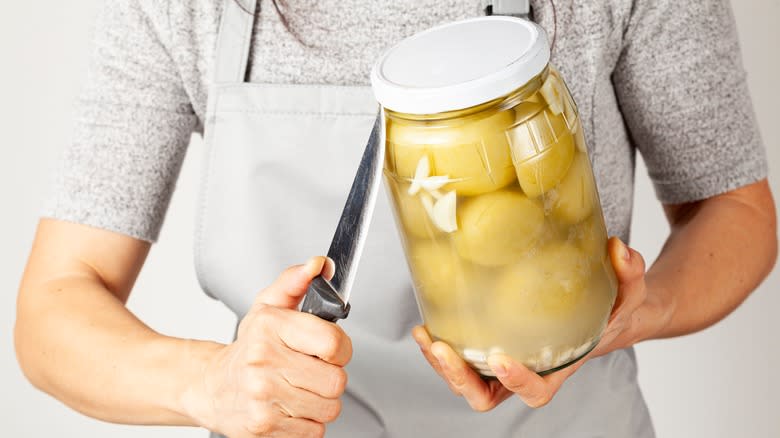 Person trying to open stuck lid with a knife