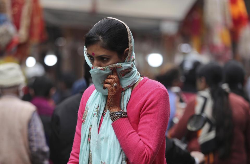 An Indian woman covers her face as a precautionary measure against the coronavirus and walks in a crowded marlet during Diwali, the Hindu festival of lights, in Jammu, India, Saturday, Nov. 14, 2020. (AP Photo/ Channi Anand)