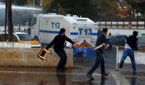 People throw stools towards an armoured police vehicle as it uses water cannon to disperse people protesting the death of Bar Association President Tahir Elci in Kurdish dominated southeastern city of Diyarbakir, Turkey, November 28, 2015. REUTERS/Sertac Kayar