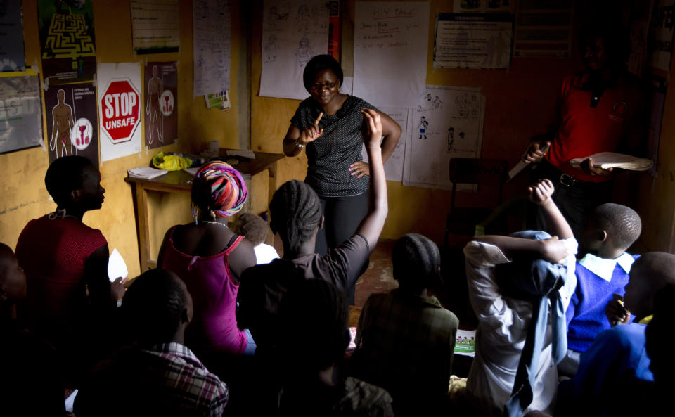 FILE - In this Monday, Feb. 16, 2015 file photo, HIV-counseling and prevention course facilitators Evelyn Ojwang, center, and Henry Owino, right, conduct an HIV prevention session entitled "Healthy Choices for a Better Future" to a group comprised of children, adolescents and adults who are either HIV-positive or at high risk of catching HIV due to their circumstances, at a center run by a Kenyan non-governmental organization in the Korogocho slum neighborhood of Nairobi, Kenya. In 2019 fewer people in many parts of sub-Saharan Africa are dying of AIDS as treatment becomes more widely available, yet some officials worry that success may be encouraging a sense of complacency. (AP Photo/Ben Curtis, File)