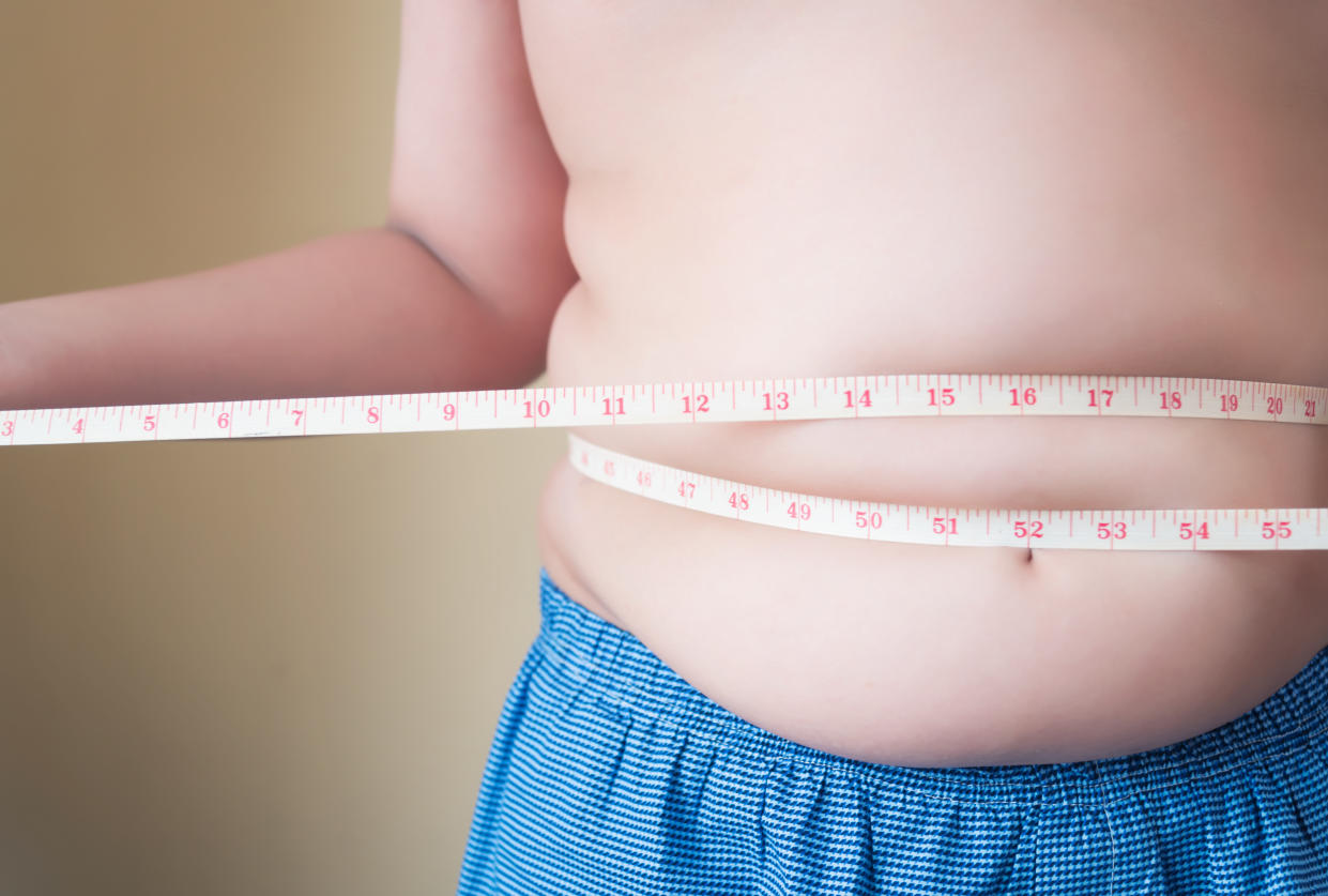 Fat boy with overweight checking out his weight isolated on white background