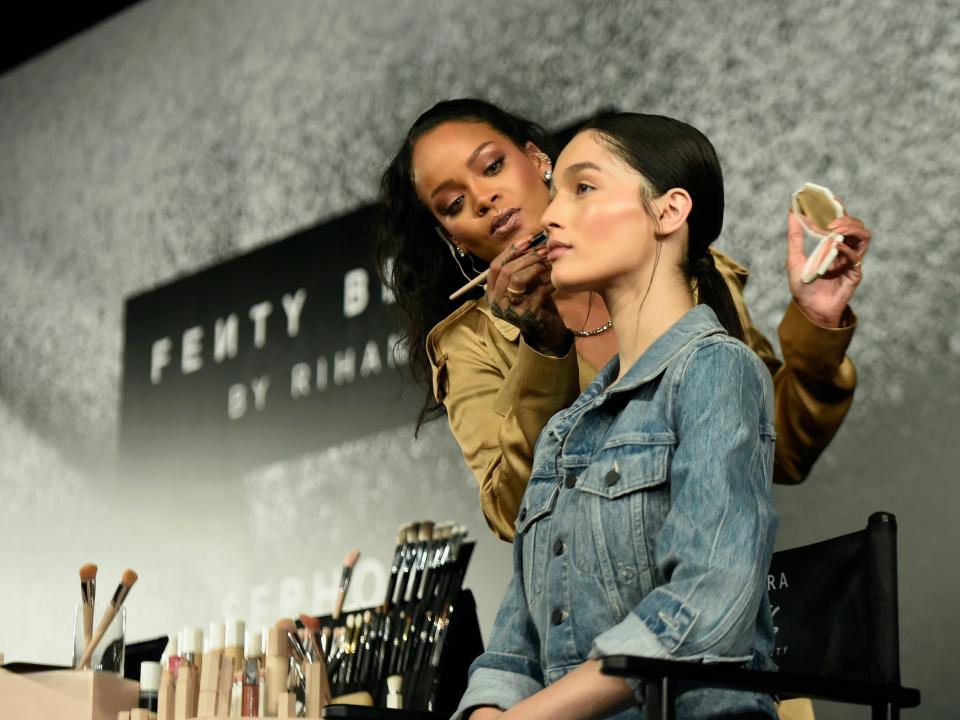 Rihanna applies Fenty Beauty makeup to a model onstage