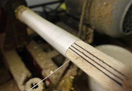 Cricket bat maker Lachlan Fisher binds with string the handle of a cricket bat at his workshop in suburban Melbourne July 27, 2009. REUTERS/Mick Tsikas