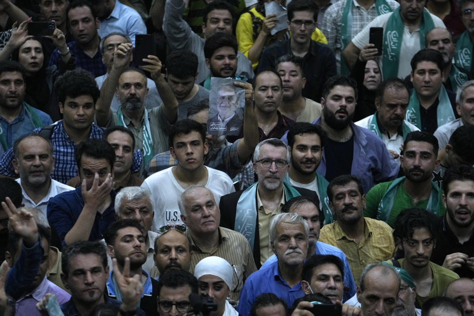 A supporter of Iranian presidential candidate Masoud Pezeshkian holds up a poster of the reformist during a campaign stop in Tehran, Iran, Sunday, June 23, 2024. (AP Photo/Vahid Salemi)