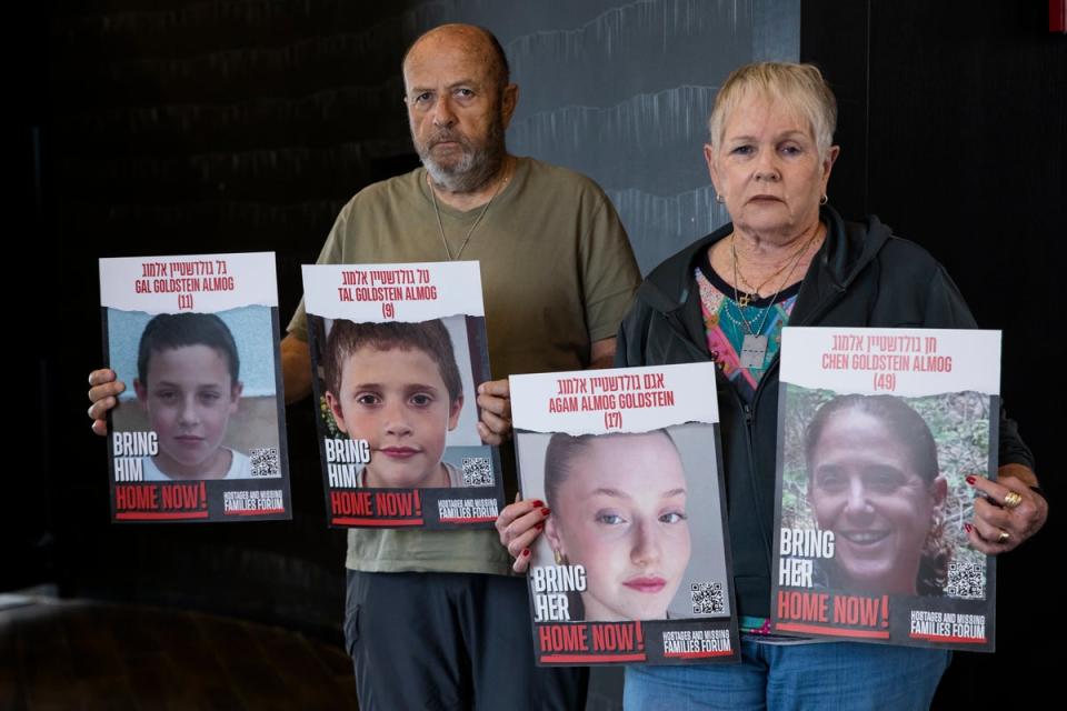 David and Varda Goldstein pose for a picture whilst holding-up photos of their 3 grandchildren, Gal, Tal and Agam, and their mother, Chen, who were kidnapped by Hamas (Getty)