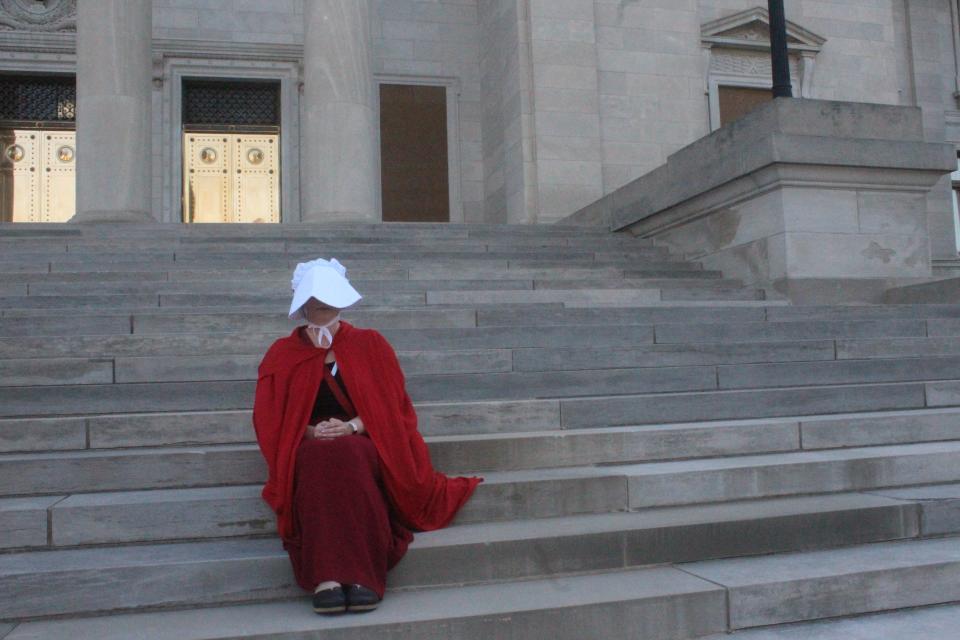 Woman dressed in attire from 'The Handmaid's Tale' protesting Supreme Court decision on abortion.