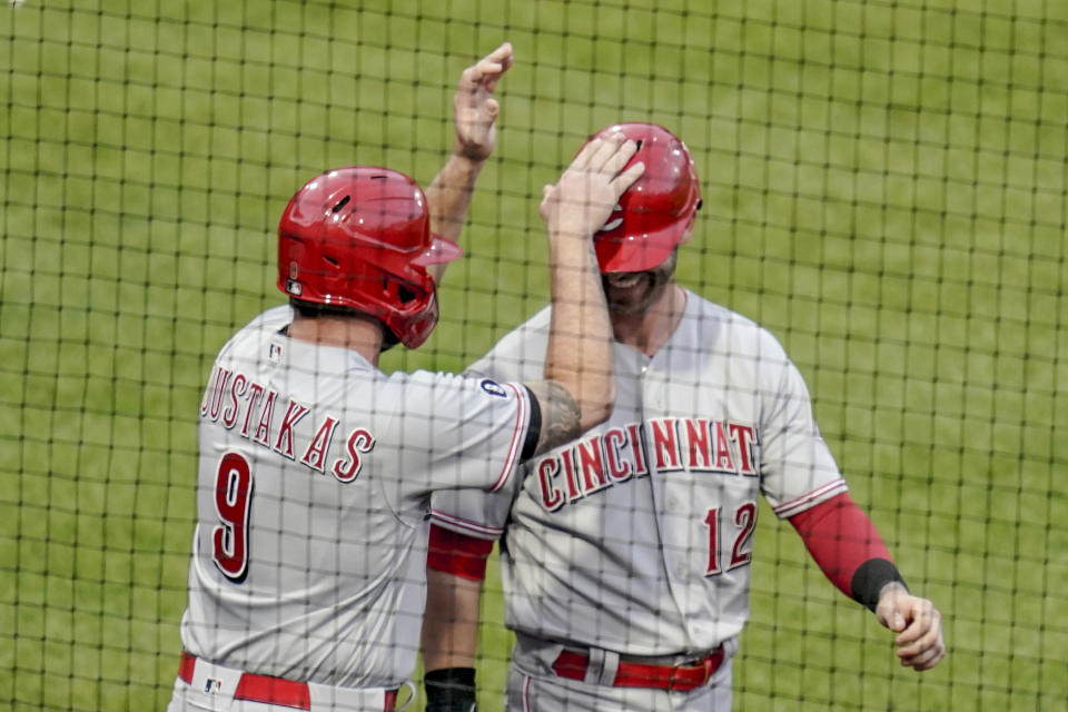 Cincinnati Reds' Mike Moustakas (9) celebrates with Tyler Naquin (12) after they scored on a double by Tucker Barnhart in the fourth inning of a baseball game against the Pittsburgh Pirates, Monday, May 10, 2021, in Pittsburgh. (AP Photo/Keith Srakocic)