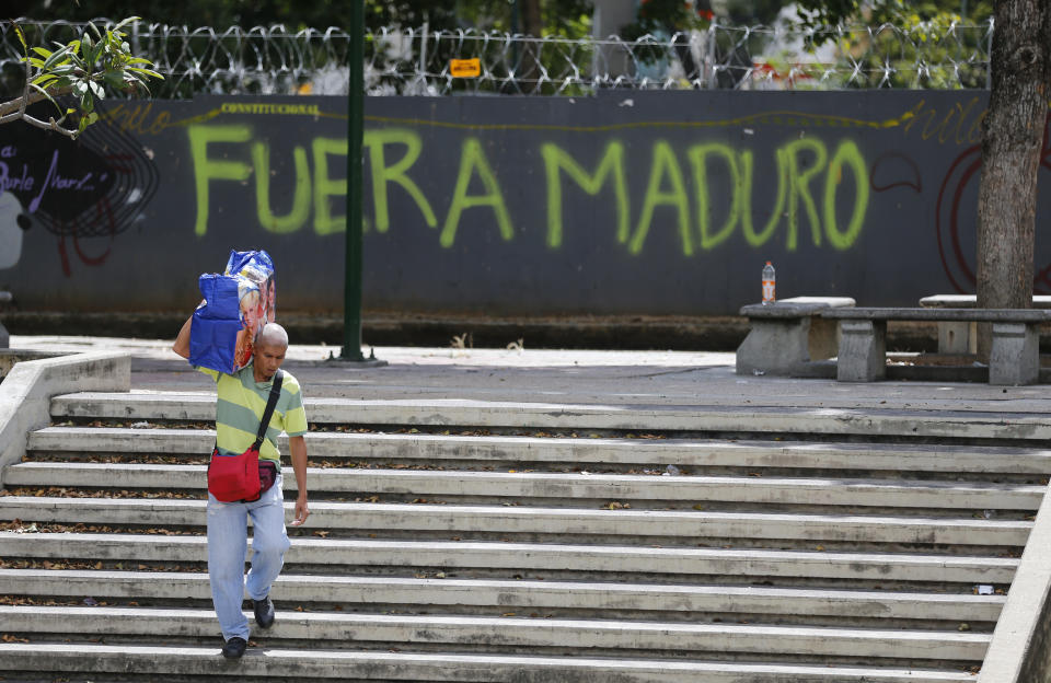 A man walks past graffiti on the wall of a vacant lot that reads in Spanish: "Get out Maduro," referring to President Nicolas Maduro in Caracas, Venezuela, Thursday, Jan. 24, 2019. Venezuelans headed into uncharted political waters Thursday, with the young leader of a newly united and combative opposition claiming to hold the presidency and Maduro digging in for a fight with the Trump administration. (AP Photo/Fernando Llano)