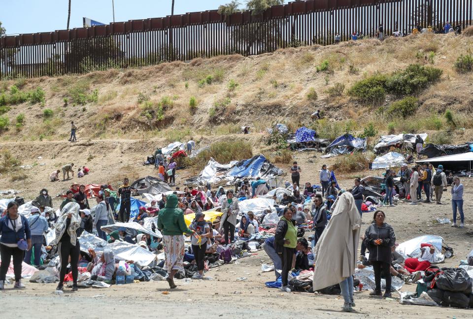 Hundreds of migrants wait on the U.S. side of the border in between two large fences near Monument Rd. close to the International Wastewater Treatment Plant in San Diego, Calif., May 11, 2023. 