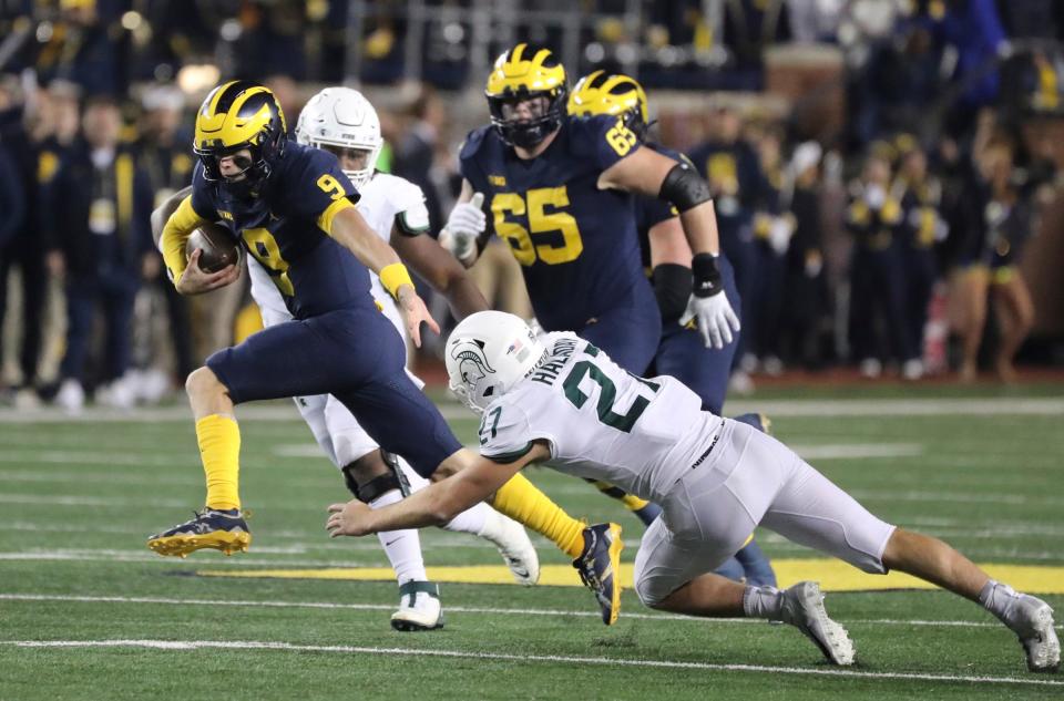 Michigan quarterback J.J. McCarthy runs by Michigan State linebacker Cal Haladay during the first half half on Saturday, October 29, 2022, in Ann Arbor.