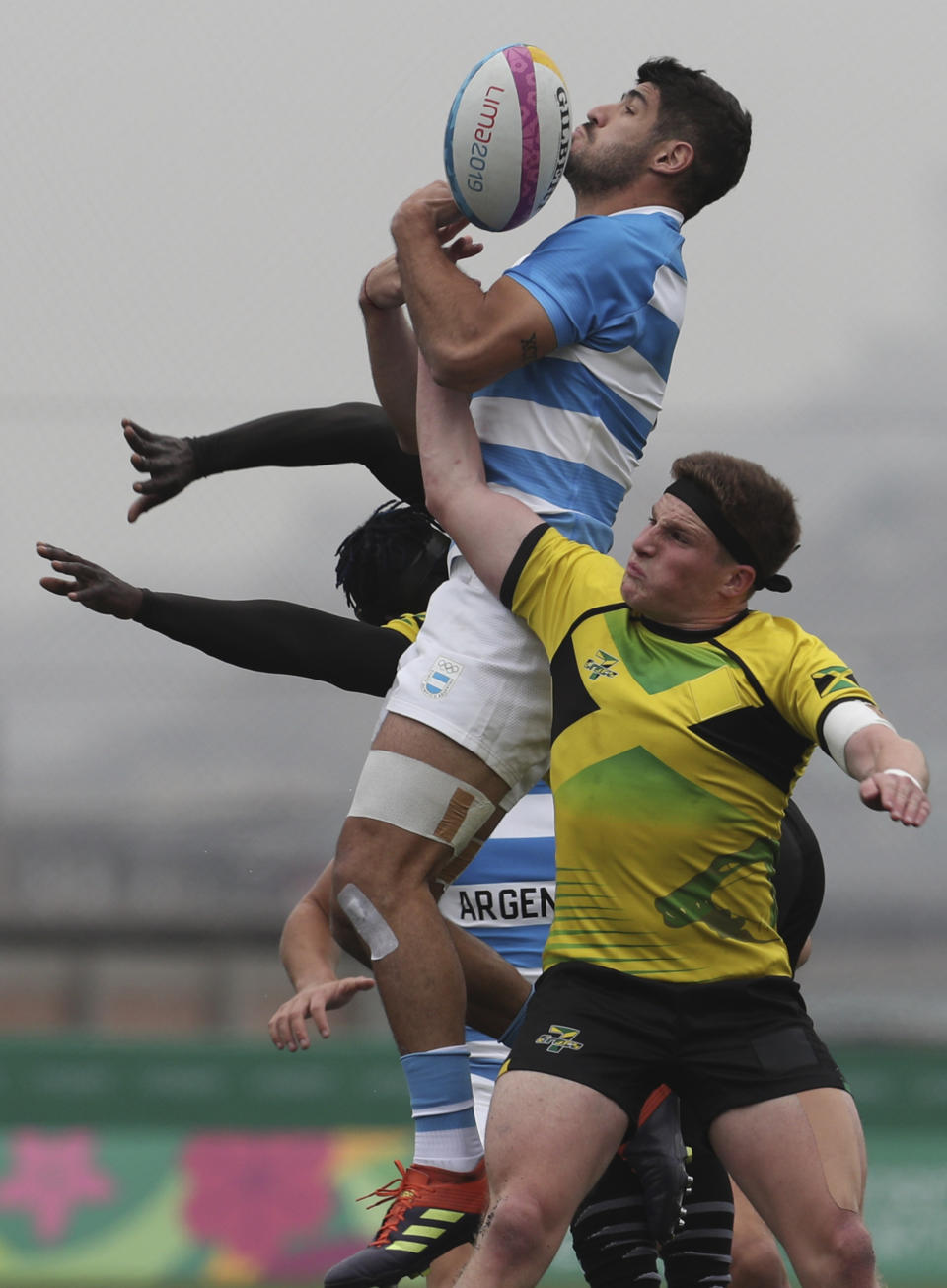 Dario Luna of Argentina, top, is tackled by Rhodri Adamson, right, of Jamaica during rugby seven match at the Pan Am Games in Lima, Peru, Friday, July 26, 2019. Argentina won the match 52-0. (AP Photo/Juan Karita)