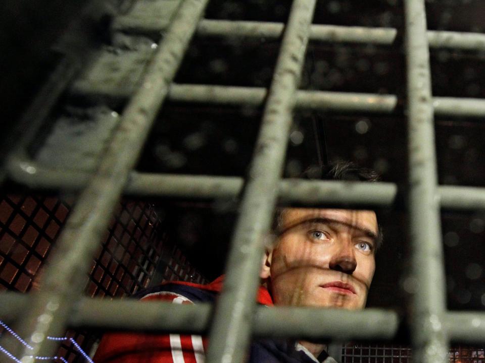 Alexei Navalny is seen behind the bars in a police van after he was detained during protests.