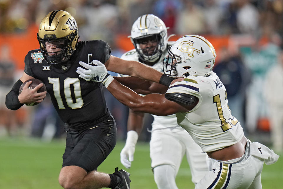 Central Florida quarterback John Rhys Plumlee (10) stiff arms Georgia Tech linebacker Paul Moala (13) after a run during the first half of the Gasparilla Bowl NCAA college football game Friday, Dec. 22, 2023, in Tampa, Fla. (AP Photo/Chris O'Meara)