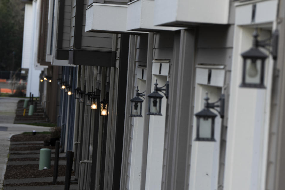 Less than 100 feet away from the so-called urban growth boundary, exterior lights are seen outside new construction homes on Thursday, Feb. 22, 2024, in the southwest Portland, Ore., suburb of Tigard. The boundary was established by a 1973 law that placed boundaries around cities to prevent urban sprawl and preserve nature and farmland. (AP Photo/Jenny Kane)