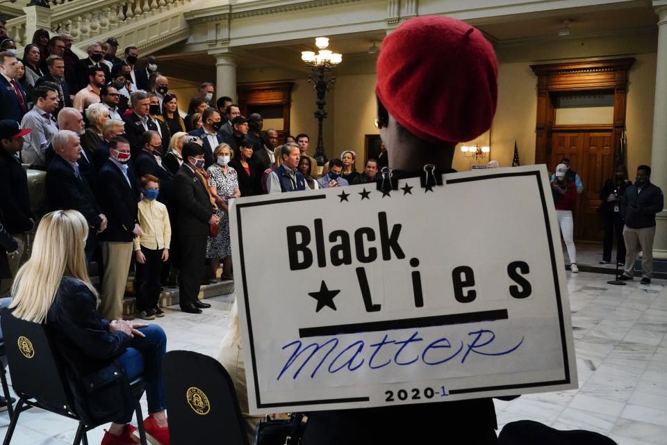 A supporter wears a "Black Lies Matter" sign as Georgia Gov. Brian Kemp speaks during a news conference at the State Capitol on Saturday, April 3, 2021, in Atlanta, about Major League Baseball's decision to pull the 2021 All-Star Game from Atlanta over the league's objection to a new Georgia voting law. (AP Photo/Brynn Anderson)