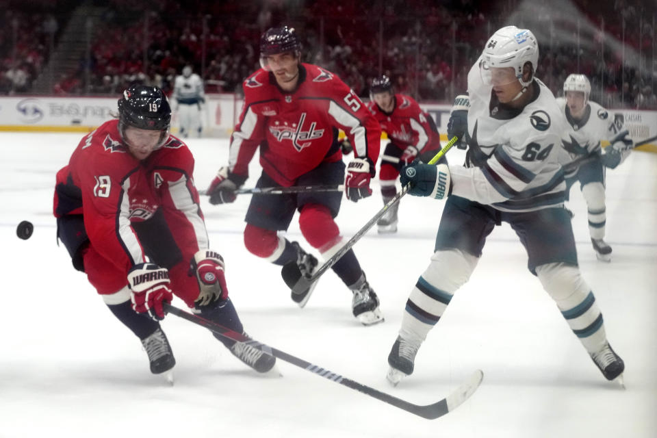 San Jose Sharks right wing Mitchell Russell (64) shoots past Washington Capitals center Nicklas Backstrom (19) and defenseman Trevor van Riemsdyk (57) in the second period of an NHL hockey game, Sunday, Oct. 29, 2023, in Washington. (AP Photo/Mark Schiefelbein)