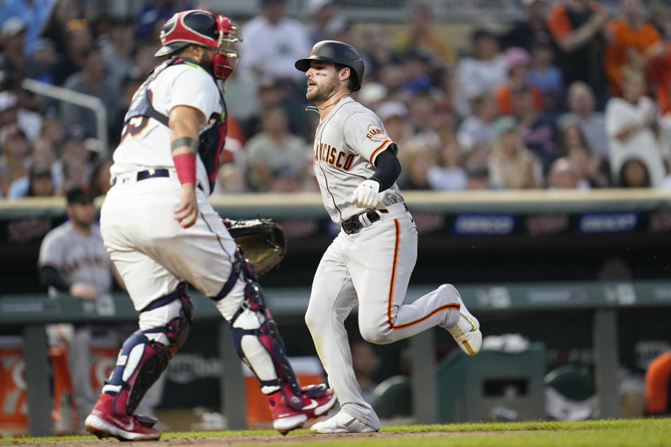 San Francisco Giants' Luis González, right, scores past Minnesota Twins catcher Sandy Leon during the fifth inning of a baseball game Saturday, Aug. 27, 2022, in Minneapolis. (AP Photo/Abbie Parr)