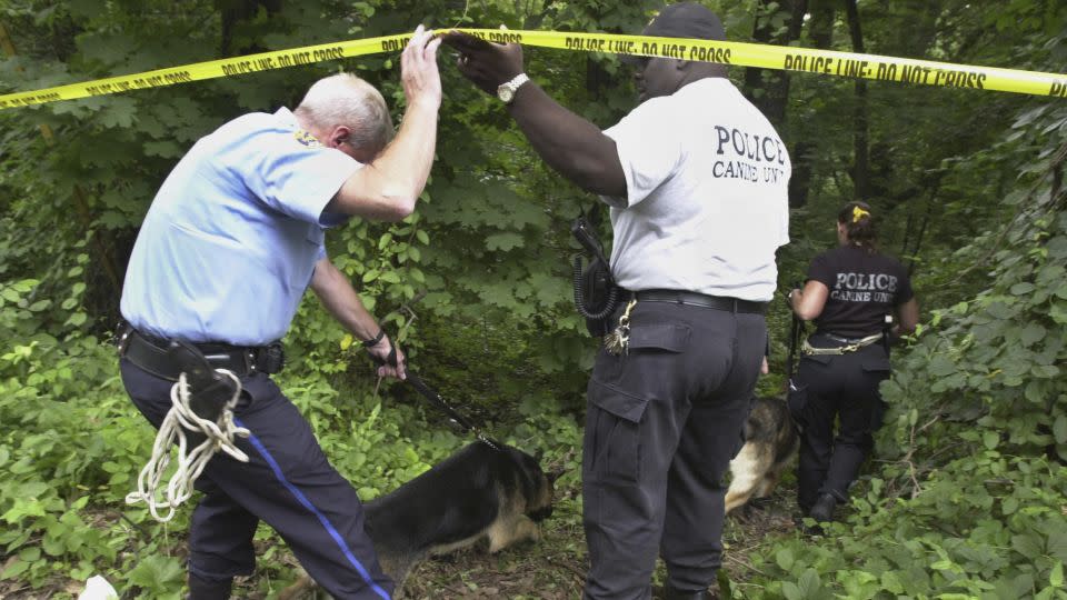 Philadelphia police walk into an area of Fairmount Park where the body of Rebecca Park was found in 2003. - Jacqueline Larma/AP