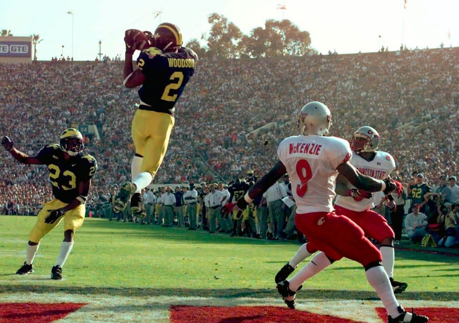 Woodson jumps high in the air to secure the interception while two Washington State receivers and another Michigan defender look on.
