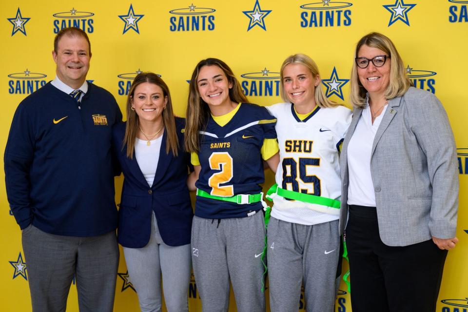 From left, Siena Heights President Douglas Palmer, Siena Heights Athletics Operations Manager Samantha Bartelotti, junior Gia Diaz, senior Emily Broman and Siena Heights Athletic Director Susan Syljebeck pose for a photo Nov. 1, after a press conference announcing the college's plan to start a competitive women's flag football team.