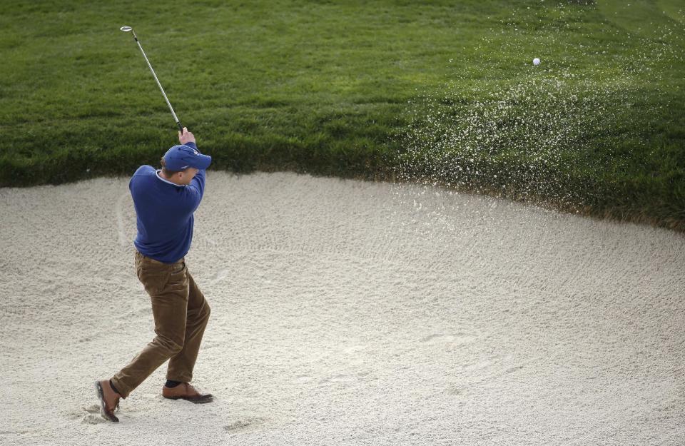 Denver Broncos quarterback Peyton Manning hits the ball out of a bunker up to the seventh green of Pebble Beach Golf Links during the second round of the AT&T Pebble Beach Pro-Am golf tournament, Friday, Feb. 7, 2014, in Pebble Beach, Calif. (AP Photo/Eric Risberg)