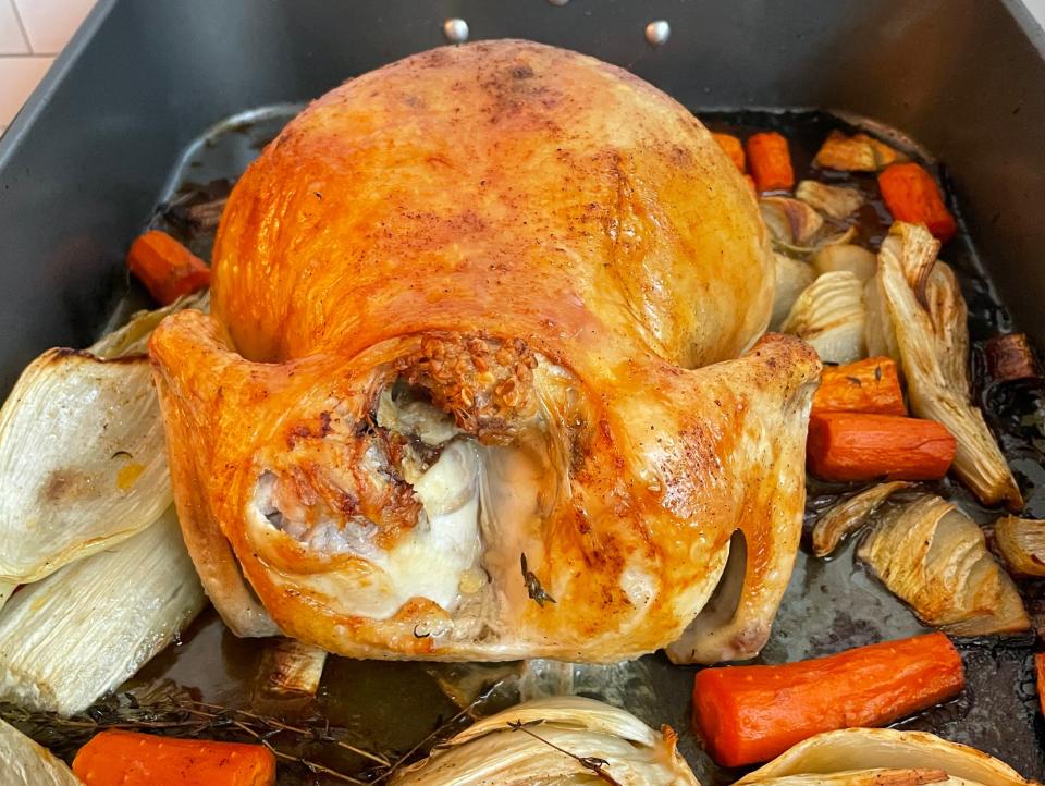 roasted chicken sitting on top of vegetables in a roasting pan