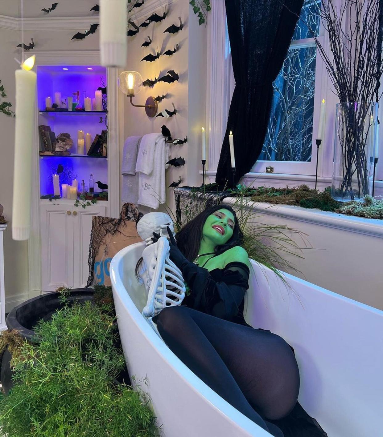 Kylie Jenner painted green lies in a bathtub
