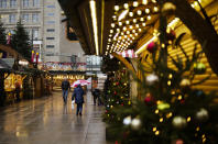 People walk across a Christmas Market on a rainy morning in central Berlin, Germany, Tuesday, Nov. 30, 2021. According to local authorities, except of shops for essential needs, only people which are vaccinated or recovered from coronavirus are allowed to enter shops. (AP Photo/Markus Schreiber)