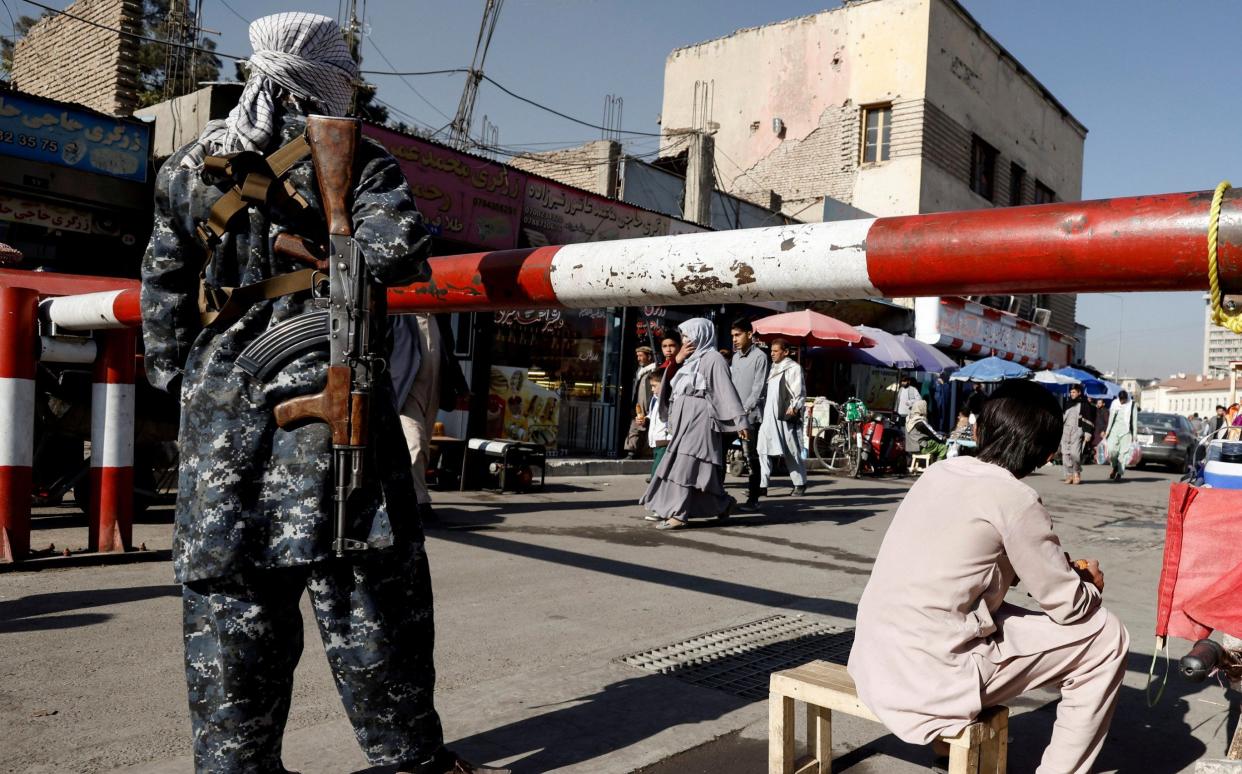 A Taliban militiaman keeps watch over a market in Kabul