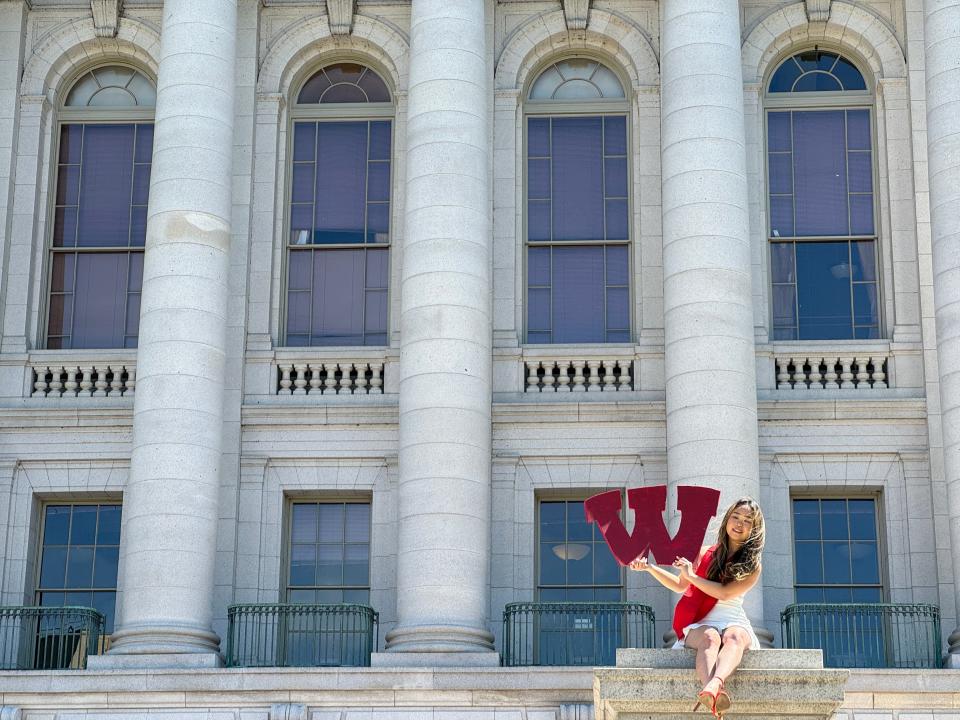 A woman poses for graduation photos May 6 at the Capitol in Madison.