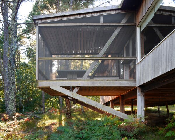 The home has a small footprint, but elements like a screened, cantilevered porch emphasize a connection with the woods.