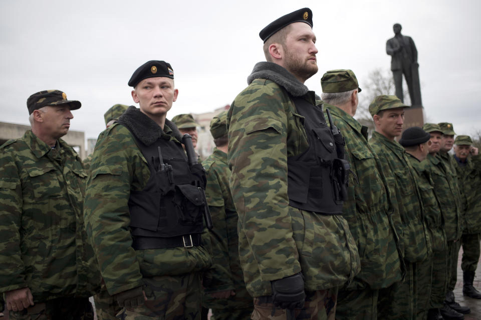 Members of the Crimean self defense forces gather for their morning briefing prior to patrolling the city at Soviet Union founder Vladimir Lenin's statue in Simferopol, Crimea, early Thursday, March 27, 2014. Crimea’s government has decided to disband self-defense forces which provided help to the Russian military which have been occupying since late February. (AP Photo/Pavel Golovkin)