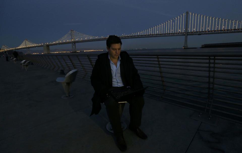 In this Wednesday, Feb. 20, 2013, photo, Artist Leo Villareal poses for photographs as he operates lights on the San Francisco-Oakland Bay Bridge on Pier 14 in San Francisco. The San Francisco-Oakland Bay Bridge has been turned into the latest, and by far the biggest, backdrop for New York artist Leo Villareal, who has individually programmed 25,000 white lights spaced a foot apart on 300 of the span’s vertical cables to create what is being billed as the world’s largest illuminated sculpture. (AP Photo/Jeff Chiu)