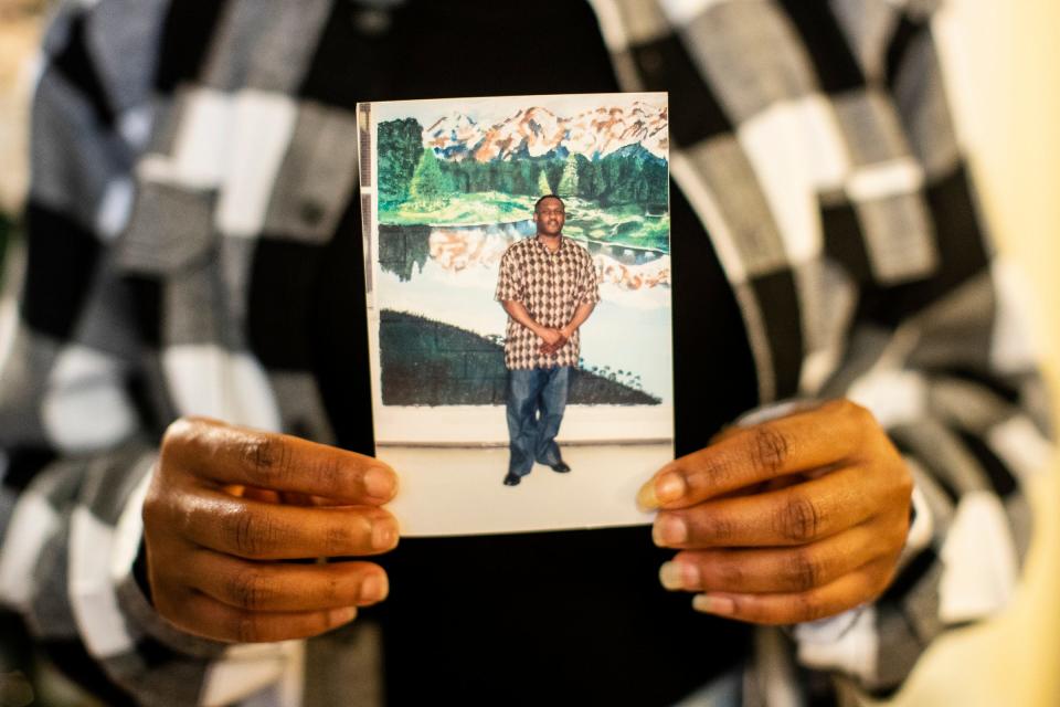 Ashley Johnson, of Huntsville, Alabama, holds a photo of her father Anthony Kyles in Pontiac on Friday, Dec. 24, 2021.