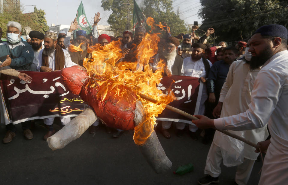 Supporters of Sunni Tehreek, a religious group, burn an effigy of French President Emmanuel Macron during a protest against the Macron and the republishing of caricatures of the Prophet Muhammad they deem blasphemous, in Lahore, Pakistan, Sunday, Nov. 1, 2020. (AP Photo/K.M. Chaudary)