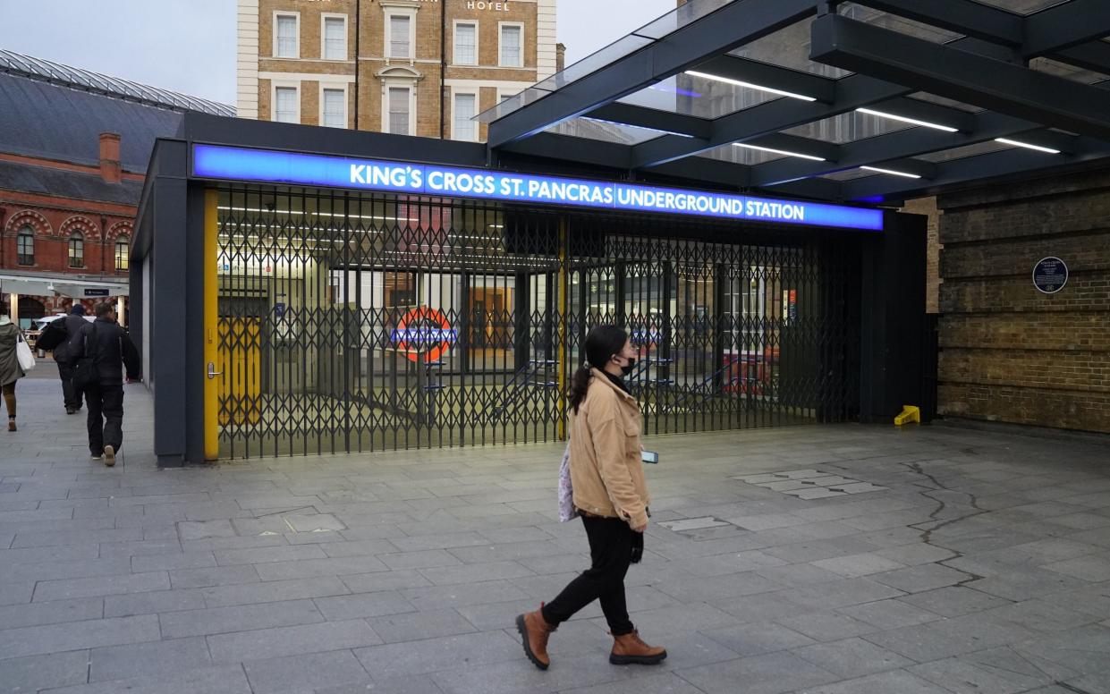 A woman walks past the closed shutters at the entrance to King's Cross station in central London during a tube strike