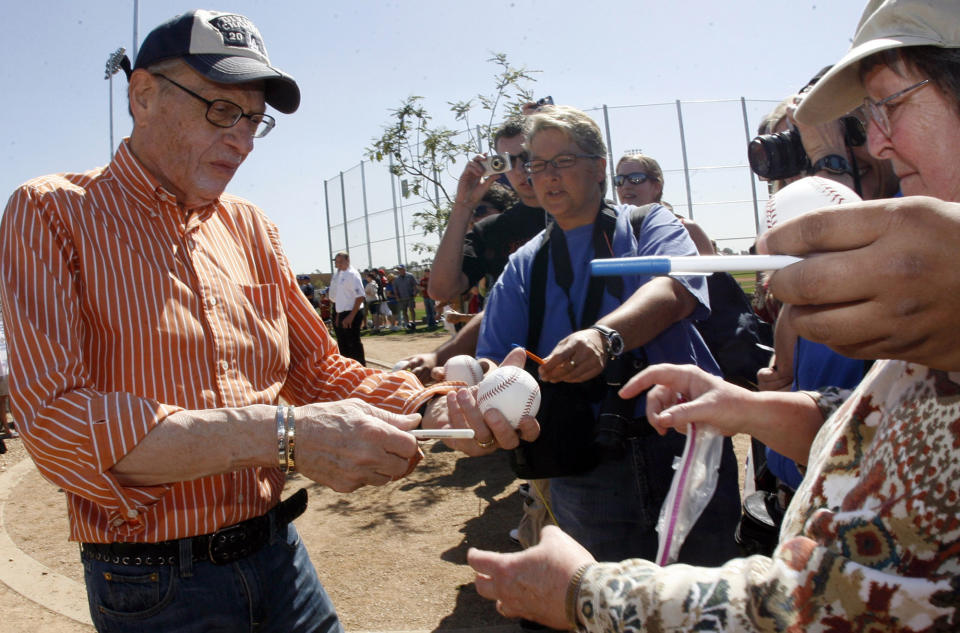 Los Angeles Dodger fan Larry King, left, signs autographs before a baseball game between the Arizona Diamondbacks and the Los Angeles Dodgers at Camelback Ranch Glendale Stadium on Tuesday March 10. 2009, in Phoenix. King, the suspenders-sporting everyman whose broadcast interviews with world leaders, movie stars and ordinary Joes helped define American conversation for a half-century, died Saturday, Jan. 23, 2021, at age 87. (Keith Birmingham/The Orange County Register/SCNG via AP)